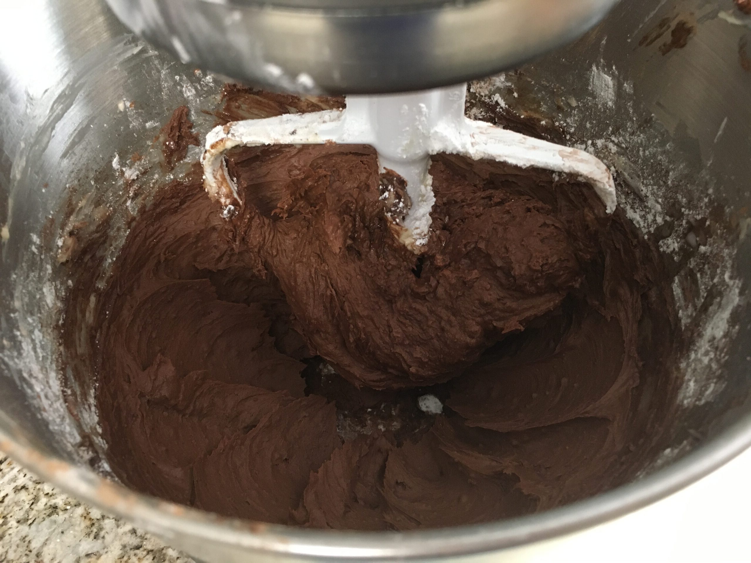 Chocolate frosting being made in a mixing bowl