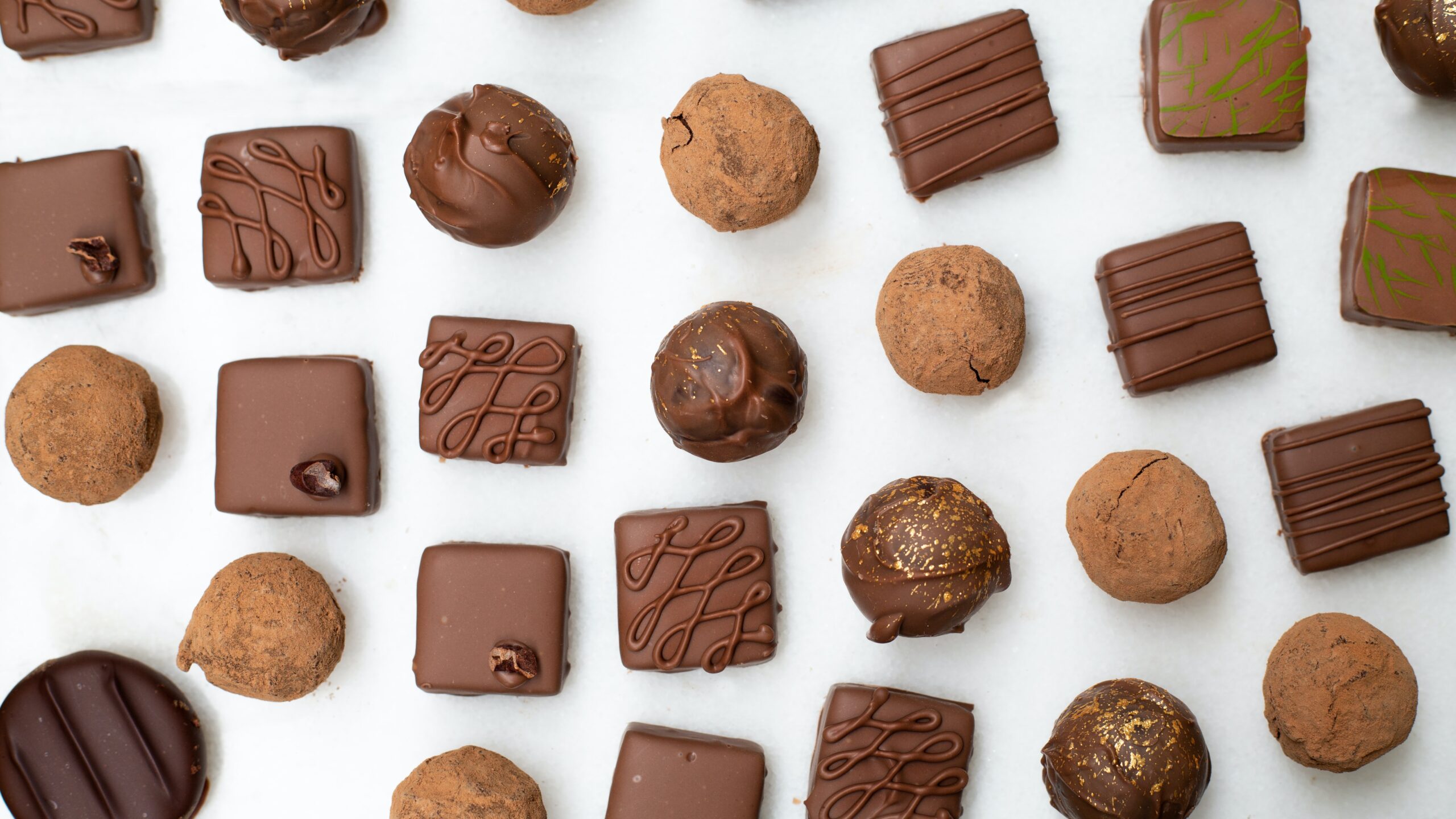 Different kinds of chocolate candies arranged on a white background