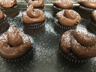 Chocolate cupcakes with chocolate frosting sprinkled with powdered sugar